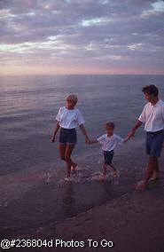 Family walking along the shore at sunset